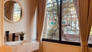 A bathroom with a white sink, a mirror, and a window with curtains. - Xinxin Youth Hostel (Shenzhen Window of the World) (Shenzhen)