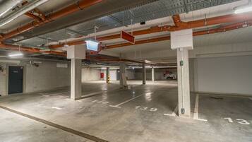 An empty parking garage with concrete floors, numbered parking spaces, and exposed ductwork.
