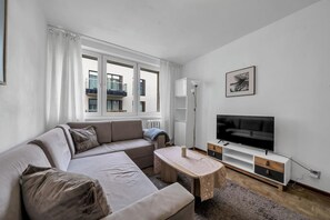 Relax in this spacious living room with a large L-shaped sofa, flat-screen TV, and floor lamp.