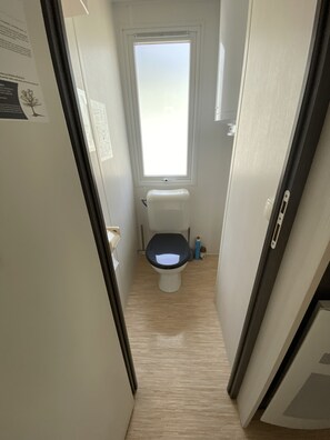 Un baño estrecho con inodoro, ventana y puerta.