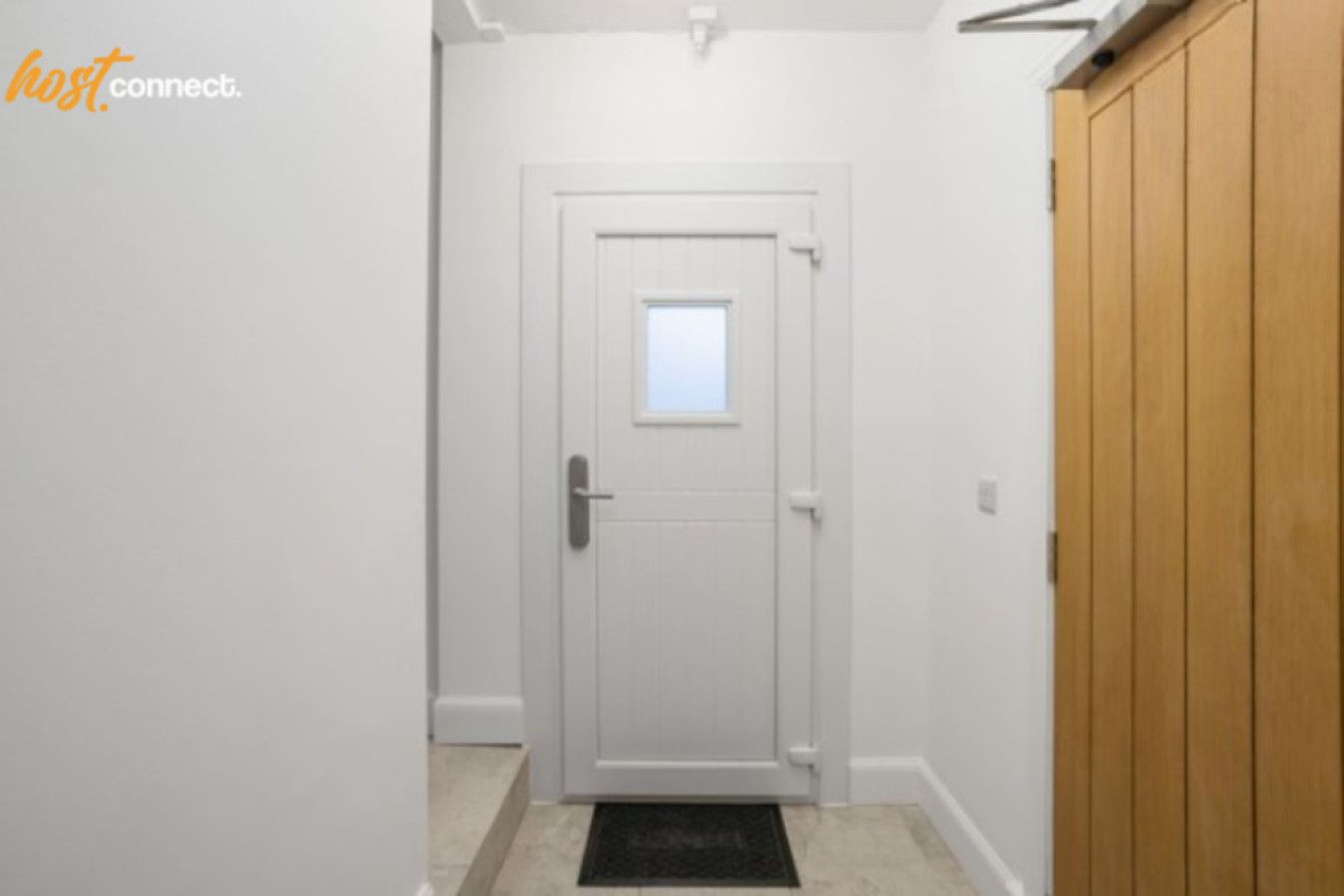 A hallway with a white door, a small window, and a wooden wardrobe.