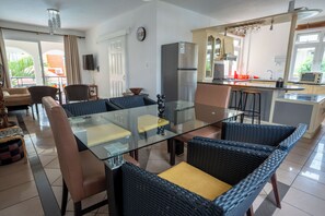 Relax in this spacious living area with a central dining table and wicker chairs, offering a view of the outdoors.