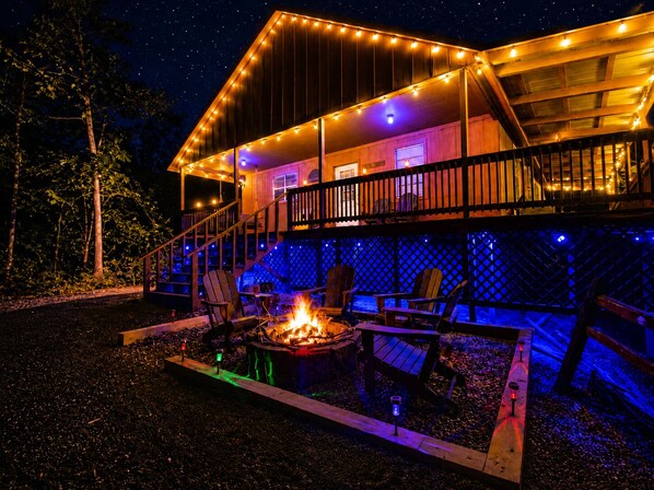 Une cabane en bois à deux étages, dotée d’une terrasse, d’un espace salon extérieur et d’un foyer.