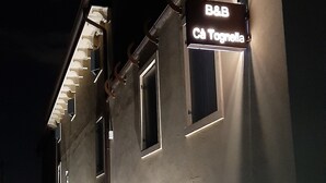 A building with a sign reading "B&B Ca Tognella" at night, featuring a modern architectural style with a flat roof and large windows. - B&B Cà Tognella (Pescantina)