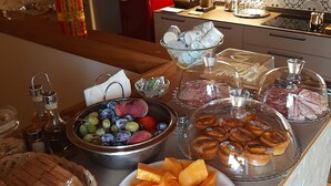 A buffet table with various food items including bread, cheese, and fruits. - B&B Cà Tognella (Pescantina)