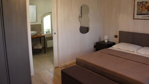 A bedroom with a bed, bedside table, and a mirror on the wall. - B&B Cà Tognella (Pescantina)