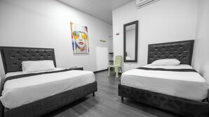 A hotel room with two beds, a green chair, a mirror, and a colorful painting on the wall. - Hotel Puerta del Sol de Uraba (Apartadó)