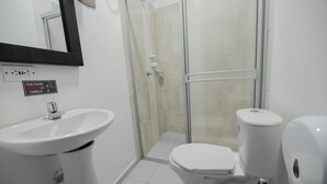 A bathroom with a white sink, toilet, and glass-enclosed shower. - Hotel Puerta del Sol de Uraba (Apartadó)