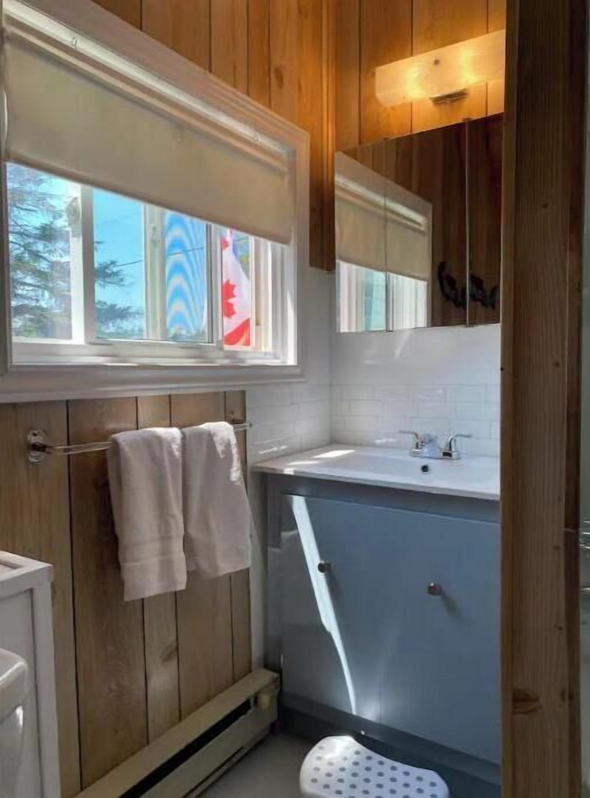 Un bagno con rivestimento in legno, una finestra, un lavandino e un water.