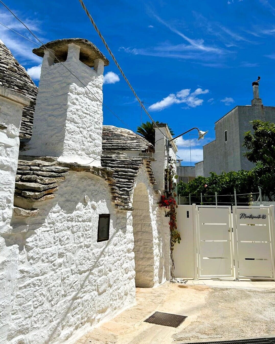 A traditional white-washed building with stone accents, a gated entrance, and a clear blue sky.