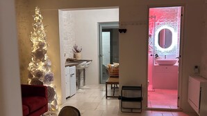 A modern kitchen with a white countertop, a red sofa, and a dining area with a table and chairs. - Montesanto 60 Suite & Relax Alberobello (Alberobello)