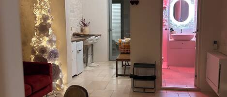A modern kitchen with a white countertop, a red sofa, and a dining area with a table and chairs.