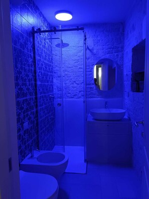 A bathroom with a glass shower enclosure, a toilet, and a sink with a mirror above it. - Montesanto 60 Suite & Relax Alberobello (Alberobello)