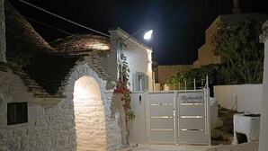A stone building with a white door and a gate, illuminated by a single light source. - Montesanto 60 Suite & Relax Alberobello (Alberobello)