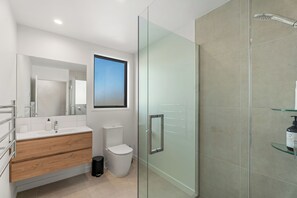 Enjoy a refreshing shower in the sleek bathroom with a glass-enclosed shower area, handheld showerhead, and large window offering a view of the sky.