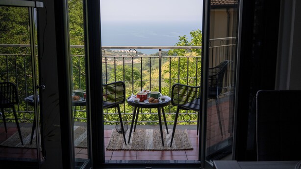 A balcony with two chairs, a small table with a plate of cookies, and a view of the sea. - Panoramic house surrounded by nature just 8 minutes from the beaches of Diamante (Maiera')