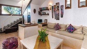 A living room with a staircase, a sofa, a coffee table with a plant, and a bookshelf with books and decorative items. - Villa Lala (Kiwengwa)