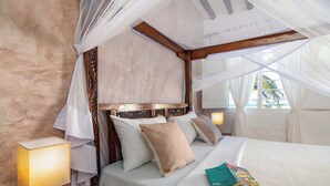 A bedroom with a canopy bed, white linens, and a bedside lamp. - Villa Lala (Kiwengwa)