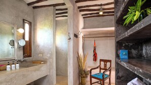 A bathroom with a large sink, mirror, and wooden chair. There is a towel rack with towels and a plant. - Villa Lala (Kiwengwa)