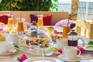 A breakfast buffet with various food items and beverages, set on a table with a view of the sea. - Villa Lala (Kiwengwa)