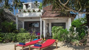 A beachside villa with two wooden sun loungers, a small table, and a chair. - Villa Lala (Kiwengwa)