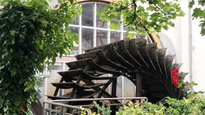 Ein Garten mit einer großen Metallskulptur, einer Holzbank und einer roten Blume.