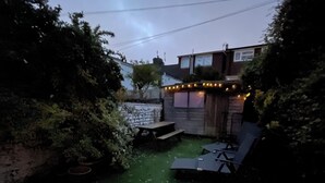 A patio with a geometric tile floor, a small seating area with a table and chairs, and a string of lights. - Stylish home with garden . Located near pubs, parks beach and town. (Brighton and Hove)