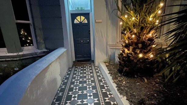 A pathway leading to a door with geometric patterned tiles and a small plant with lights. - Stylish home with garden . Located near pubs, parks beach and town. (Brighton and Hove)