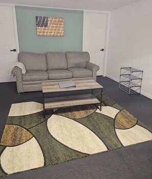 A living room with a grey sofa, a coffee table, and a patterned rug. - Private Waterfront Suite  (Lilly)
