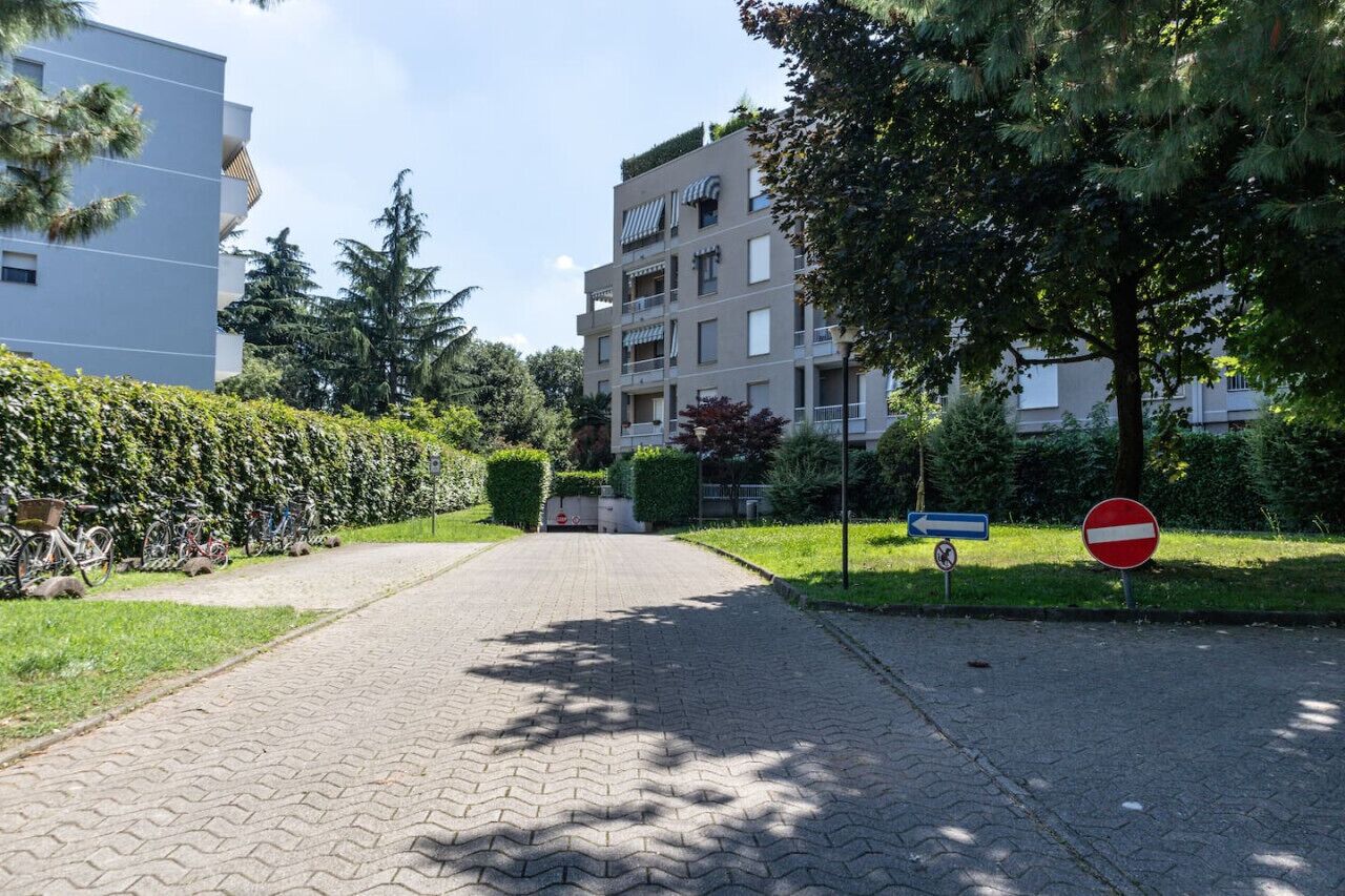 A paved pathway leading to a building with a no-entry sign and a directional sign.
