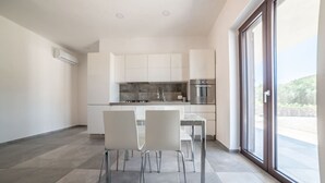 A modern kitchen with white cabinets, stainless steel appliances, and a dining area with chairs. - Casa Vacanze Signora Cinzia (Torchiara)