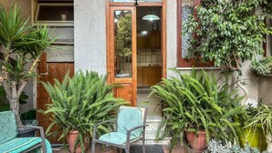Un espace patio avec une porte en bois, des plantes en pot, une chaise et une table.