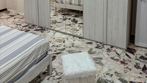 Une chambre à coucher avec un lit, une armoire et un petit tabouret.