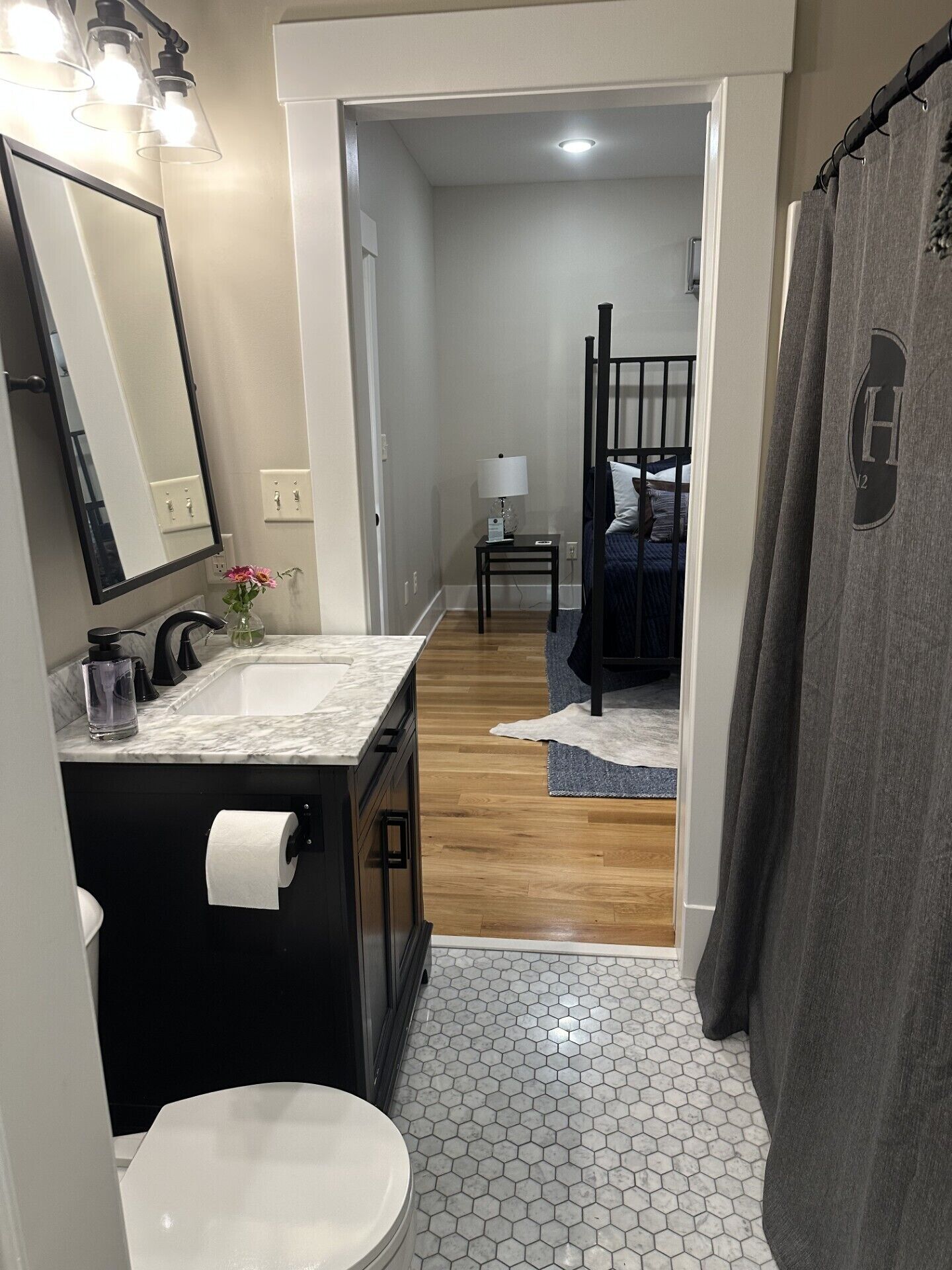 Une salle de bain avec un lavabo en marbre, des toilettes et un rideau de douche.