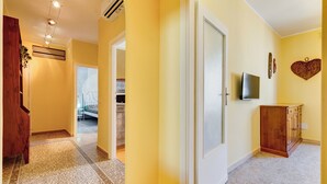 A hallway with a wooden cabinet, a television, and a heart-shaped decoration on the wall. - The Popes' Oasis - 2 steps from Trastevere and Historical Center (Roma)