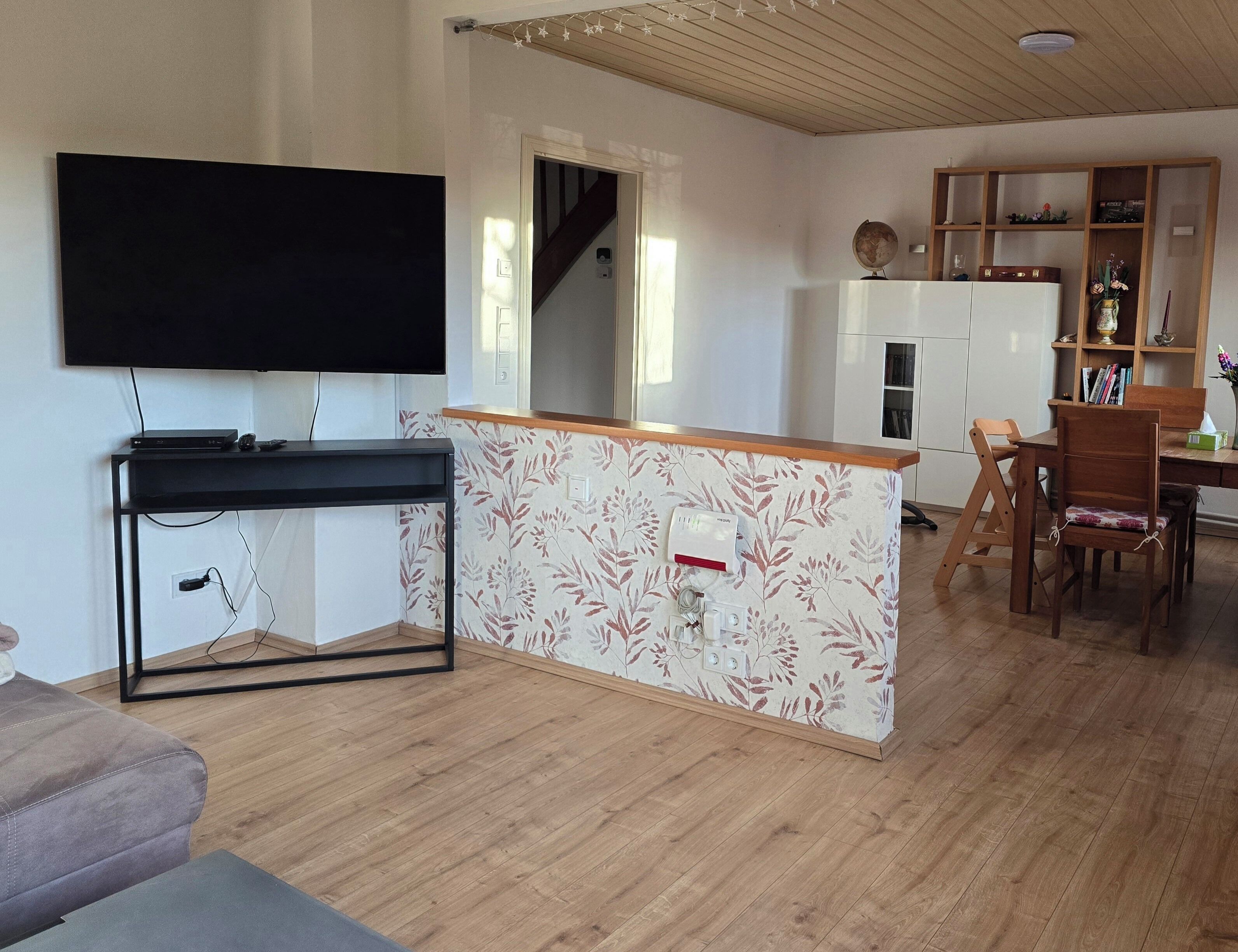 Un salon moderne doté d’un téléviseur à écran plat, d’une table à manger en bois et d’un coin cuisine.