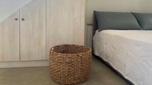 A bedroom with a bed, a woven basket, and a wardrobe. - Detached comfortable stone house with wonderful views 10 min from the sea (Kardamyli)