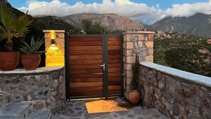 A wooden gate with a stone wall and potted plants on a balcony overlooking a mountainous landscape. - Detached comfortable stone house with wonderful views 10 min from the sea (Kardamyli)