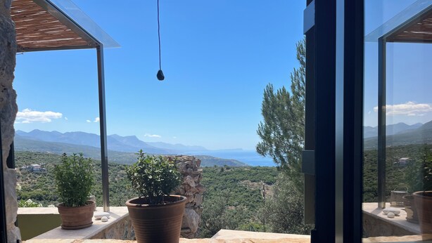 A room with a large window overlooking a mountainous landscape and a clear blue sky. - Detached comfortable stone house with wonderful views 10 min from the sea (Kardamyli)