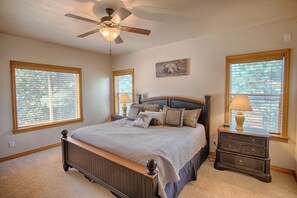 A bedroom with a bed, a nightstand, a dresser, a ceiling fan, and two windows with blinds. - Family friendly 🐻 Lazy Bear Lodge 🐻 20 guests 🌲Walk  to Woodland Lake 🌲 (Pinetop-Lakeside)