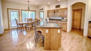 Una cocina amplia con armarios de madera, una isla de encimera de granito y una zona de comedor con sillas de madera.