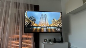 A television mounted on a wall, displaying a cityscape with a clock indicating 17:45.