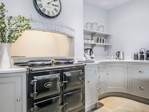 A kitchen with a stove, cabinets, a clock, and a plant. - This stunning property is a real treat for history lovers. (Syderstone, near Fakenham)