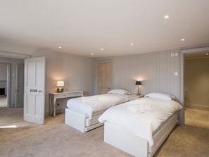A hotel room with two beds, a desk, a chair, and a wardrobe.
