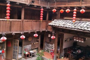 Un edificio tradicional de madera con varios niveles, faroles rojos colgando y un tejado de baldosas.