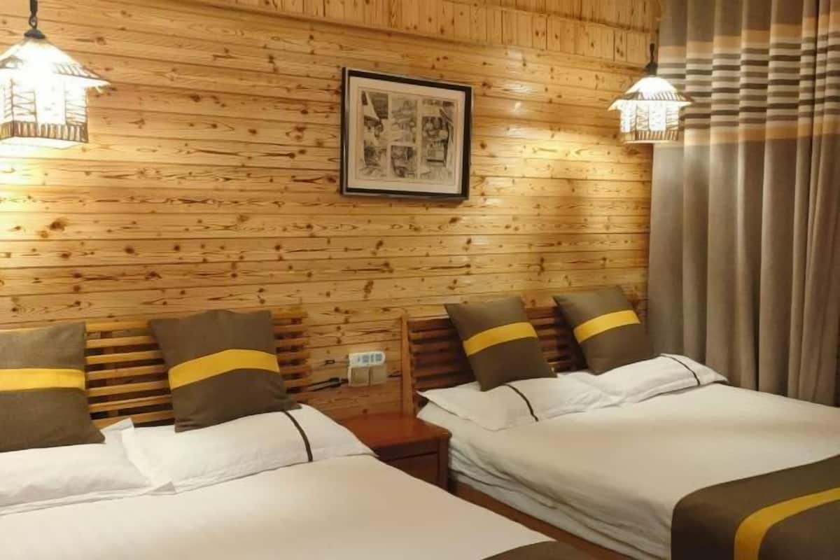 A wooden-paneled room with two beds, a framed picture on the wall, and two hanging lamps.