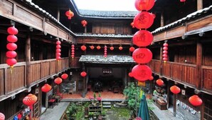 Une cour intérieure traditionnelle, avec un sol en bois et des lanternes rouges suspendues au plafond.