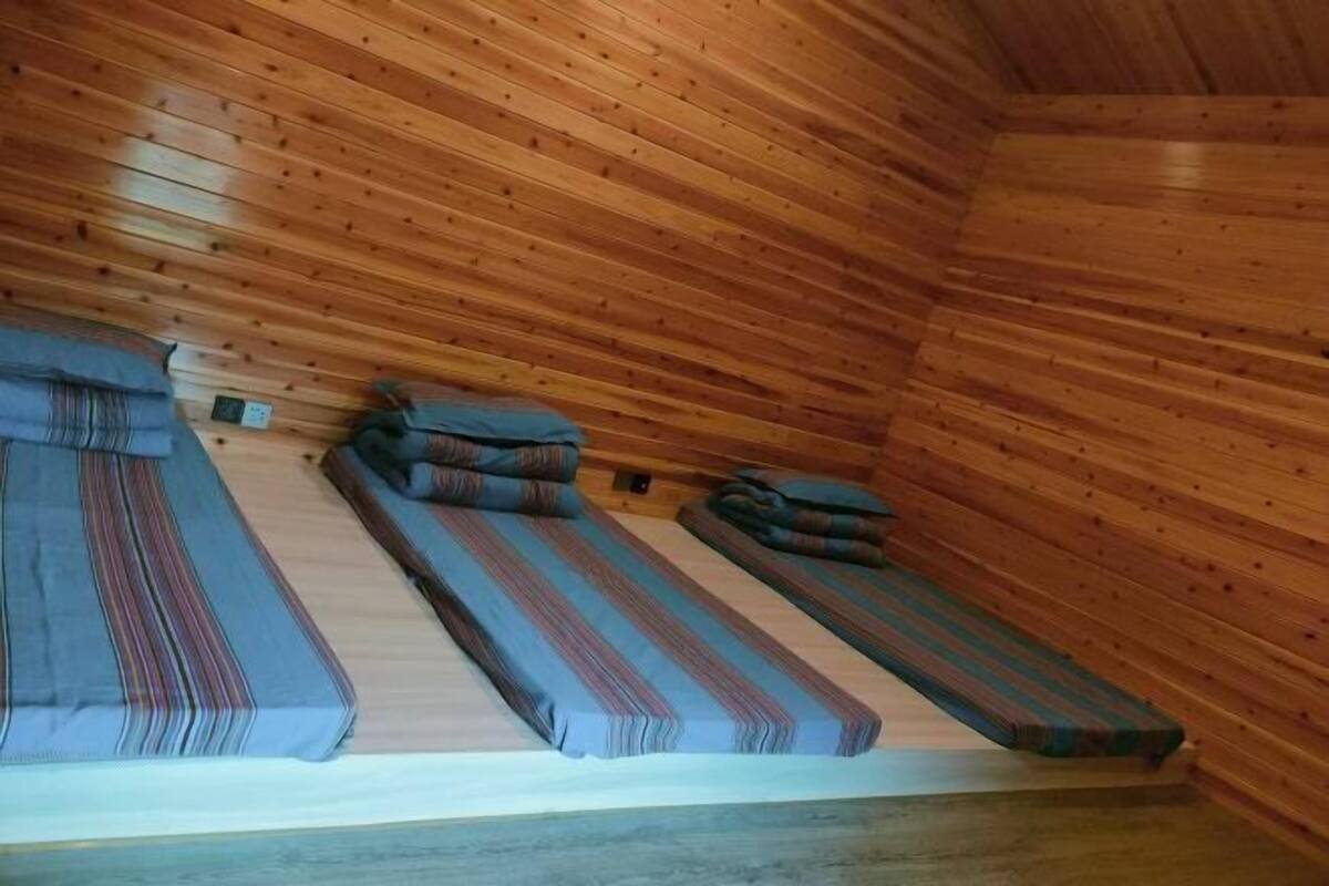 A cabin with three bunk beds, each with a striped blanket and pillow.