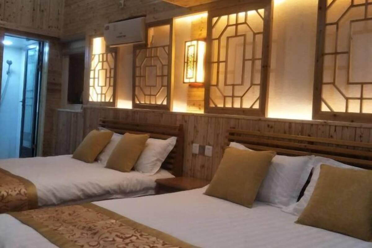 A hotel room with two beds, wooden headboards, and decorative wall panels.
