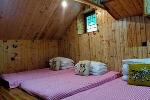 A cozy wooden room with two beds, each with pink checkered bedding and decorative pillows. - Qingdelou Inn (Nanjing County)